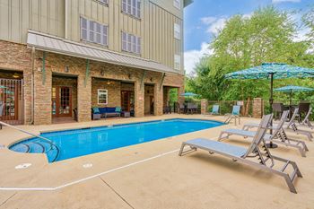 A pool area with sun loungers and a building in the background.